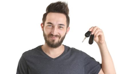 Lächelnder Fahrer vor seinem mit einem Autokredit finanzierten Wagen